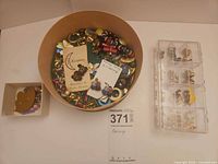 Overview of round box filled with assorted earrings, small box and plastic organizer
