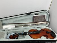 Open case showing violin, bow, paperwork and cloth
