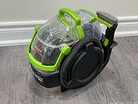 Front left view showing cleaner body, hose, brush tool, tanks