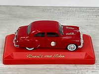 Left front side view of the red Solido Coca-Cola 1950 Chevrolet sedan model on display base
