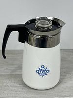 Left front view showing Cornflower graphic, handle, stainless band, lid