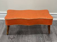 Top and side view of orange vinyl ottoman showing overall shape and condition
