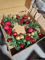 Full view of wreath inside box showing arrangement and ornament colors