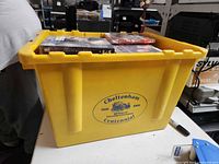 Yellow plastic tote marked Cheltenham Centennial filled with DVD cases