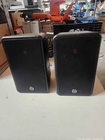 Front view of both black Monitor Audio speakers on table