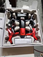 Drone in molded packaging showing red and black propellers