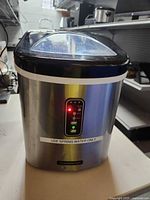 Front view showing Tramontina branding and control panel illuminated