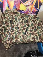 Top view of camouflage cart caddy with attached multicolor strap and red carabiner visible