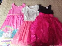 Three dresses laid side by side on bed