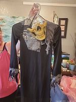 Full view of Grim Reaper robe on hanger with gauze accents and skull mask hung at neckline