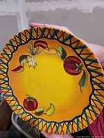 Front view of yellow vegetable-motif platter held upright