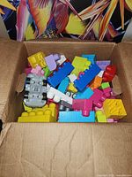 Open box showing multicolor Duplo blocks and grey car base