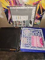 Overview of black storage case, blue Fiskars embossing board with templates, clear carry case standing behind