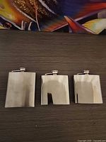 Front view of three stainless steel hip flasks
