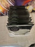 Stack of eleven square coasters in holder, showing edges and quantity