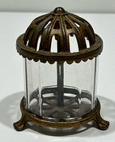 Full view of coin bank front showing cast iron dome, glass body, feet