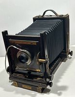 Three-quarter view of camera showing bellows extended, lens, brass hardware, cable release