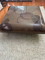 Square lacquer coffee table top view showing floral motif and gloss finish