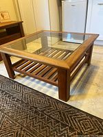 Cherry wood coffee table angled view showing glass top and slatted shelf