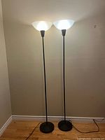 Full view of two identical black floor lamps illuminated