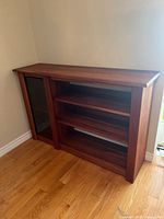 Full view of cherrywood sideboard against wall showing glass door and shelves