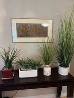 Four tabletop planters with faux greenery on console table