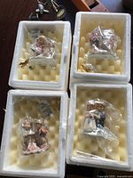 Four sealed figurine ornaments in original foam trays