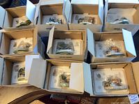 Ten boxed Danbury Mint Miniature Village pieces in open cartons showing contents in styrofoam