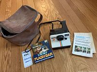 Group shot of camera, flash bar box, carry bag, pamphlet
