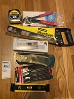 Full lot overview showing tape measure, saw, pliers, rule, boxed bit set, multi-tool, pry bar set, level