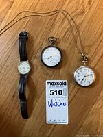 All three watches laid out on floor with auction tag visible