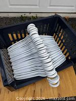 White plastic hangers stacked inside navy blue storage bin