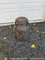 Full view of metal milk can on gravel