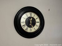 Front view of round black framed wall clock mounted on wall