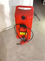 Front view of red 14-gallon Flo N' Go fuel caddy showing cap, handle and hose.