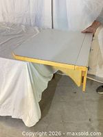 Tabletop opened showing white laminate surface and wood support bracket