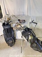 Two golf bags filled with clubs, loose driver and push cart visible