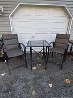 Full view of table and two chairs set against garage