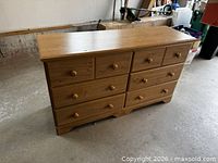 Front view of pressboard dresser showing eight drawers and wooden knobs