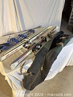 Overall view showing two pairs of skis, snow blades, goggles and ski bag