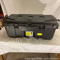Front view of black plastic storage trunk showing latches and label