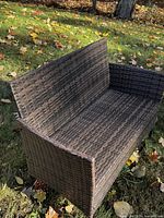 Front angle of synthetic wicker loveseat on grass