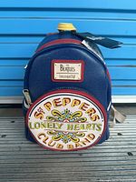Front view of blue Loungefly Beatles mini backpack with Sgt. Pepper artwork