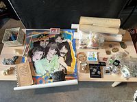 Overview of entire lot on table including poster, figurines, notebook, pins, Lego box, rolled posters