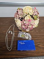 Full lot view with floral arrangement, necklace, earrings, push pins, blue card
