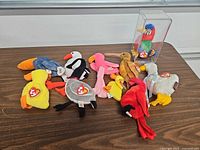 Group shot of all ten bird plush toys and display box on table