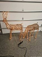 Two gold-toned lighted deer sculptures plugged in and illuminated