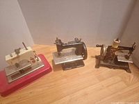 All three miniature sewing machines side by side showing overall condition and styles