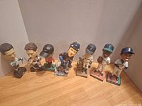 All seven bobbleheads lined up on floor, left angled view