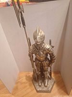 Full view of knight armour stand with poker and brush